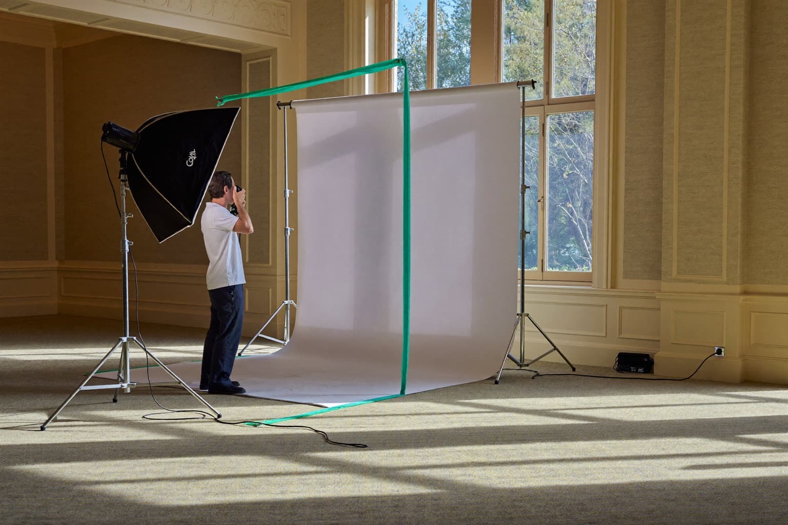 An open-air photo booth with a ring light and sequin backdrop set up in an empty event space before guests arrive