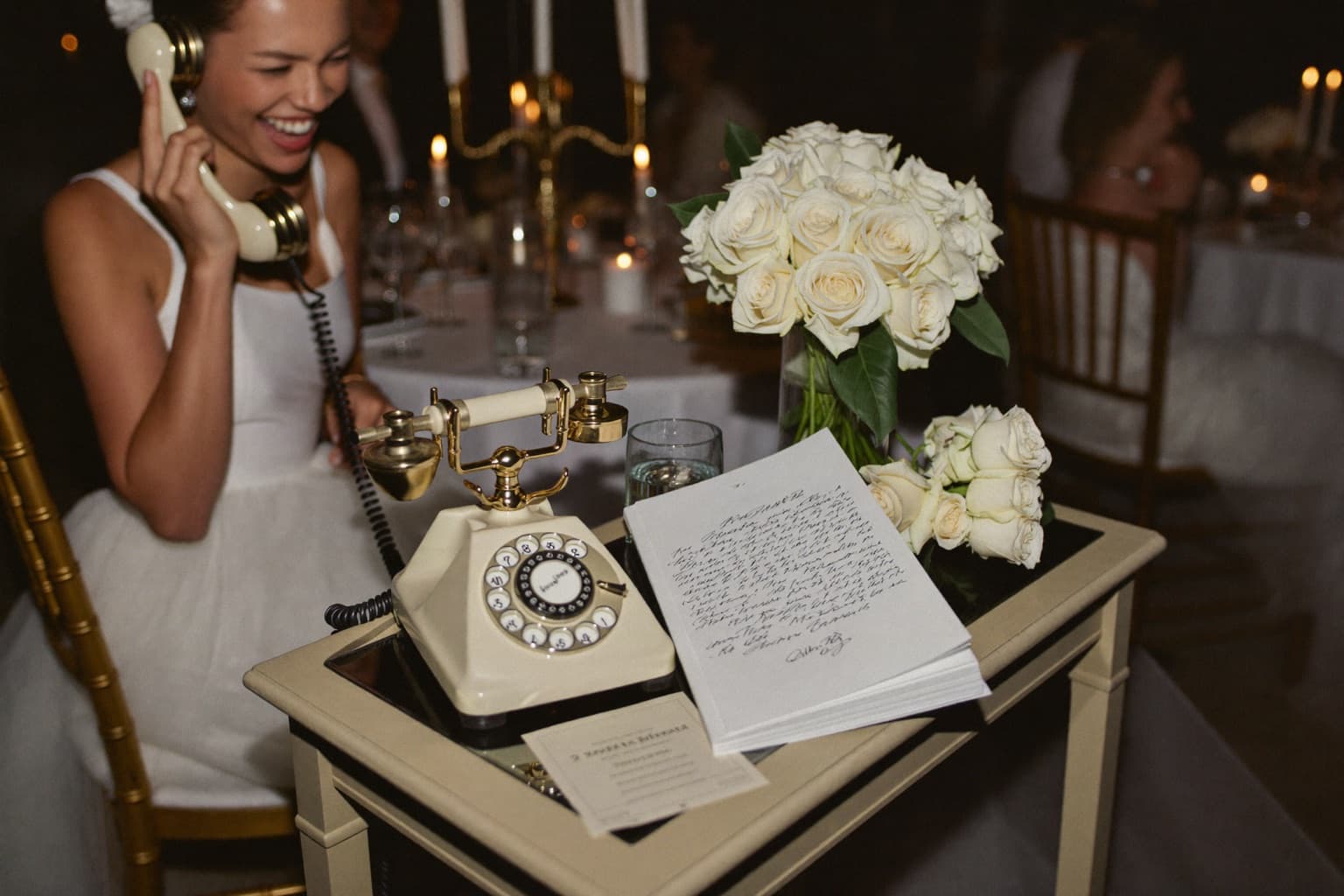 Wedding guest holding the handset of a vintage rotary telephone set up as an audio guestbook on a decorated reception table